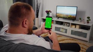 homem usando smartphone com tela verde para maquete de chroma key de espaço de cópia. gestos de rolagem. video