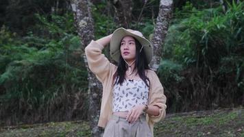 linda mulher asiática se sentindo revigorada e curtindo a natureza na floresta. garota gosta de acampar na floresta de férias. viagens ao ar livre e tema da natureza. video