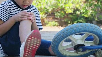 menina triste sentada no chão depois de cair de bicicleta no parque de verão. criança se machucou enquanto andava de bicicleta. video