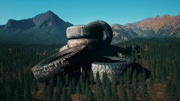 concept of environmental pollution with big old tires in mountain forest photo