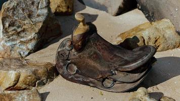 very old horse saddle on sand beach photo