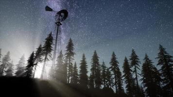 retro windmill in mountain forest with stars. hyperlapse photo