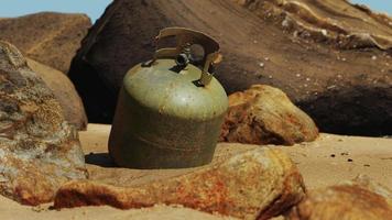 antiguo cilindro de gas de cocina en la playa de arena foto