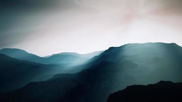 black rocky mountain silhouette in deep fog photo