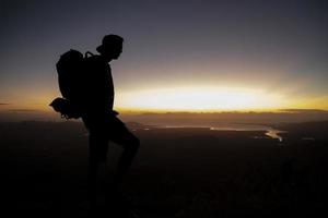 silueta de un montañero en la cima de una montaña al amanecer foto