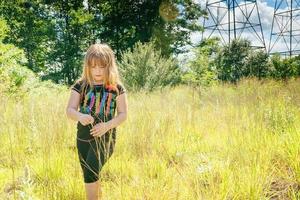 portrait of a beautiful girl on the nature. The in camomile field.Little holding bouquet daisies standing in blue sky background photo