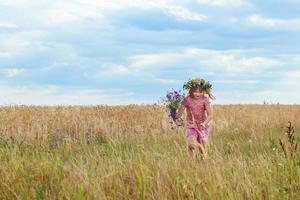 beautiful little girl with a wreath in the wheat field photo