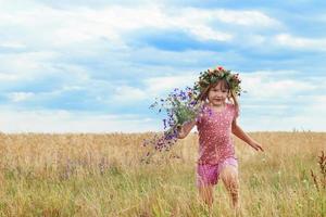 beautiful little girl with a wreath in the wheat field photo