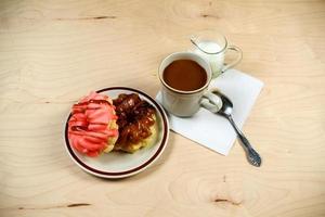 Two delicious sugared ring donuts served on white plate with a cup of hot drink photo