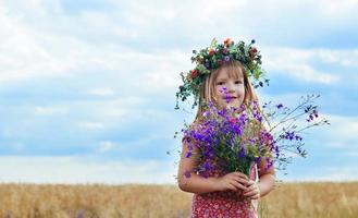 little girl with a wreath his head field of wheat photo