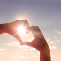 corazón en forma de mano contra la puesta de sol. concepto del día de san valentín foto