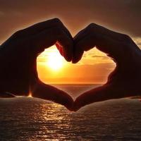 corazón en forma de mano contra la puesta de sol. concepto del día de san valentín foto