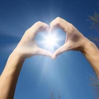 corazón en forma de mano contra la puesta de sol. concepto del día de san valentín foto