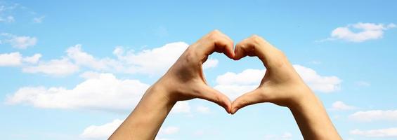 corazón en forma de mano contra la puesta de sol. concepto del día de san valentín foto