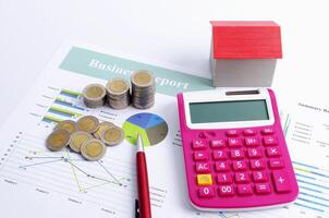 Business finance concept with coins stack and calculator red house and pen photo