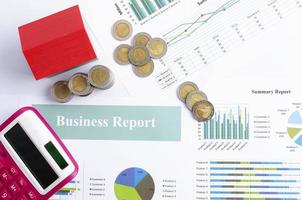 informe de finanzas comerciales con monedas de dinero y casa roja y fondos de calculadora arriba foto
