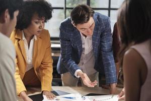 El equipo y los colegas multirraciales de los compañeros de trabajo intercambiaron ideas, discutieron la estrategia de marketing, la colaboración de ideas y la planificación de proyectos comerciales en la mesa de conferencias de una oficina en el lugar de trabajo de la reunión del personal. foto