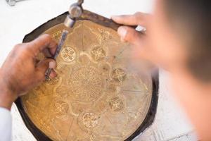 craftsman engraving patterns on the tray. masters of Central Asia. manual copper minting photo