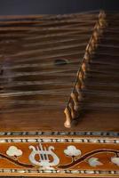 ancient Asian stringed musical instrument on black background with backlight. the similarity of the harp and psaltery. closeup photo