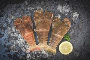Raw flathead lobster shrimps on ice, fresh slipper lobster flathead for cooking on dark background in the seafood restaurant or seafood market, Rock Lobster Moreton Bay Bug photo