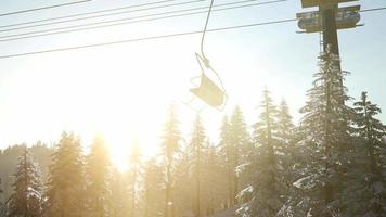 téléski vide. silhouette de télésiège en haute montagne au-dessus de la forêt au coucher du soleil video