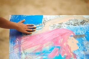 Woman hand smearing blue paint on canvas, art expression at outdoor art festival, art improvisation photo