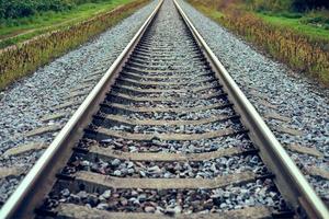 Railway track line going into distance, railroad train track with crushed stone, two parallel rails photo