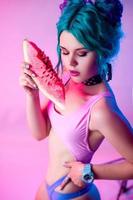 portrait of a bright woman with blue hair eating a watermelon in neon light photo