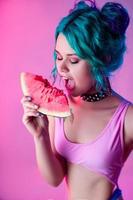 portrait of a bright woman with blue hair eating a watermelon in neon light photo