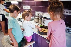 madre con hijos cocinando en la cocina, momentos felices de los niños. foto