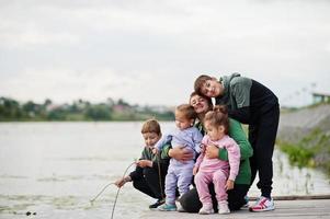 amor de padre papá con cuatro hijos al aire libre en el muelle. la familia numerosa deportiva pasa el tiempo libre al aire libre. foto