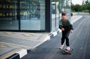 Teenager boy in a sports suit rides on longboard. photo