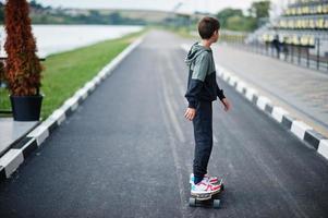 niño adolescente en un traje deportivo paseos en longboard. foto