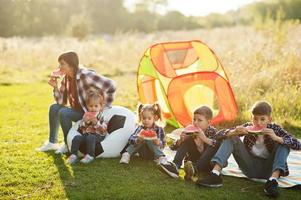 Family spending time together. Four kids with mother eat watermelon outdoor. photo