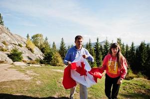 Happy Canada Day. Couple with large Canadian flag celebration in mountains. photo