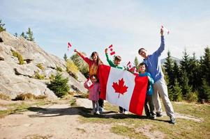 Happy Canada Day. Family with large Canadian flag celebration in mountains. photo