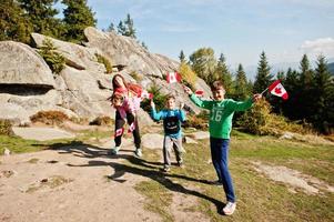 Happy Canada Day. Family of mother with three kids hold large Canadian flag celebration in mountains. photo