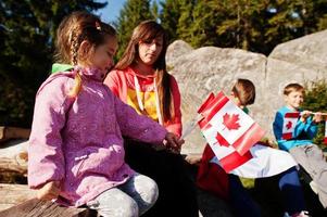 Happy Canada Day. Family of mother with three kids hold large Canadian flag celebration in mountains. photo