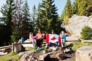 feliz dia DE CANADA. la familia de la madre con tres hijos celebra una gran celebración de la bandera canadiense en las montañas. foto