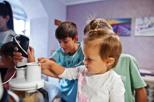 madre con hijos cocinando en la cocina, momentos felices de los niños. trabajar con una licuadora. foto