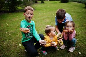 Four kids with doughnuts at evening yard. Tasty yummy donut food. photo