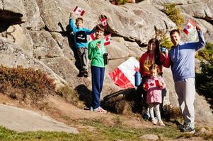 Happy Canada Day. Family with large Canadian flag celebration in mountains. photo