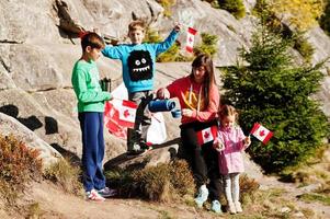 Happy Canada Day. Family of mother with three kids hold large Canadian flag celebration in mountains. photo