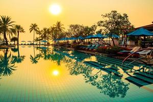 palm tree with umbrella chair pool in luxury hotel resort at sunrise times photo