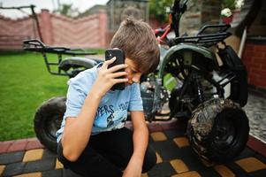 Boy in four-wheller ATV quad bike with mobile phone. photo