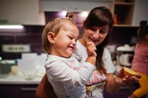 Mother with kids cooking at kitchen, happy children's moments. Mom hold a lemon. photo