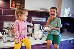 Kids cooking at kitchen, happy children's moments. Brother with sister together. photo