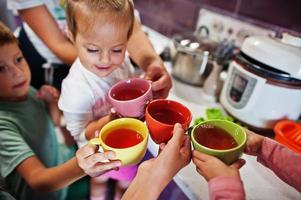 Mother with kids drink compote at kitchen, happy children's moments. photo