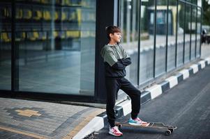 muchacho adolescente en un traje deportivo con longboard. foto