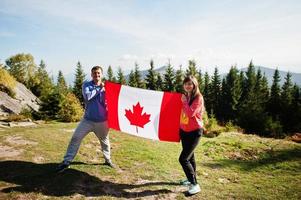 Happy Canada Day. Couple with large Canadian flag celebration in mountains. photo